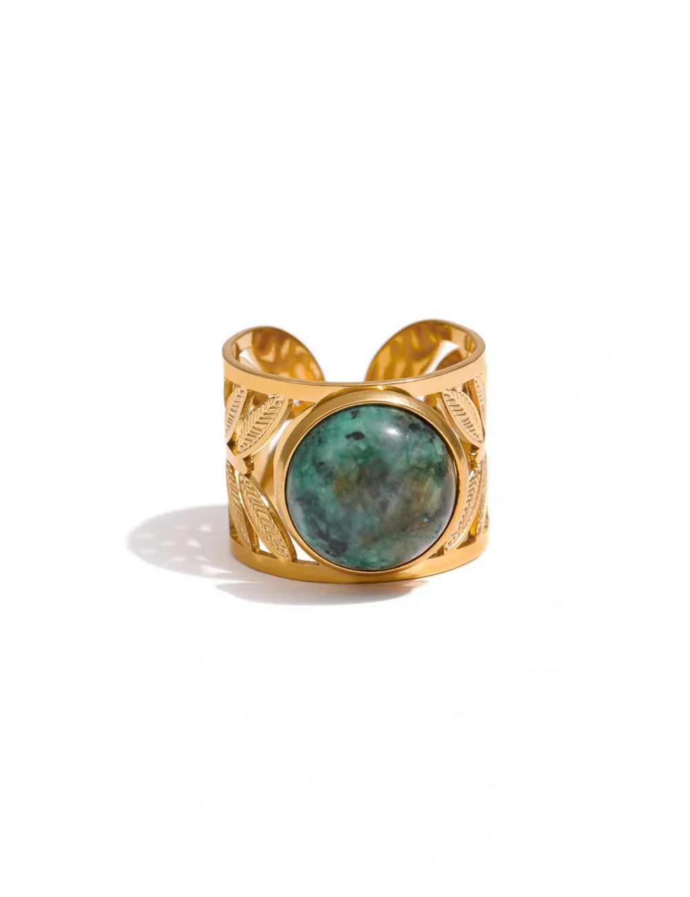 The Turquoise Statement Ring is a wide gold-plated band with leaf engravings and a large round turquoise centerpiece, embodying classic bohemian style. Shown against a white background.