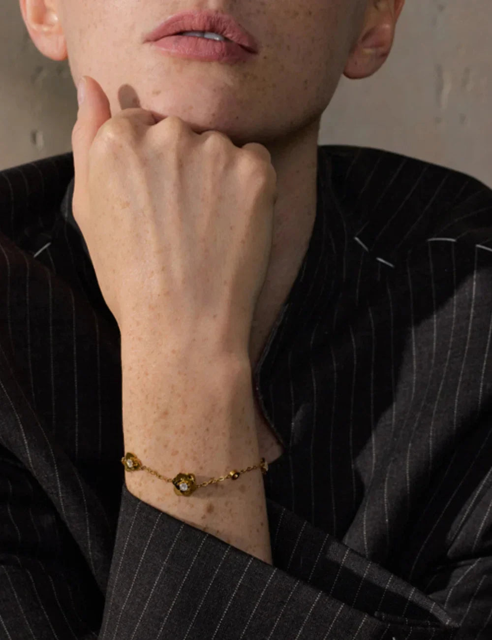 Close-up of a woman wearing a delicate gold bracelet with crystal details, elegant jewelry photography